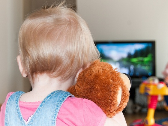 Bebê assistindo televisão e segurando bicho de pelúcia - Vasaleks / Shutterstock